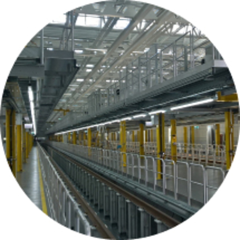 Instandhaltungshalle für Schienenfahrzeuge mit Gleisbett, gelben Stützelementen und mehrstöckigen Dacharbeitsbühnen.