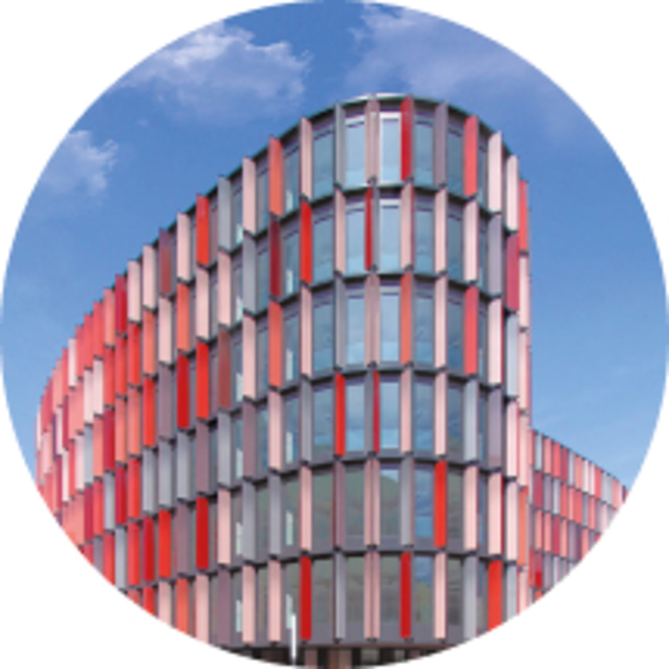 Moderne Glasfassade eines Bürogebäudes mit vertikalen, rot-grauen Lamellen zur Fassadensteuerung.